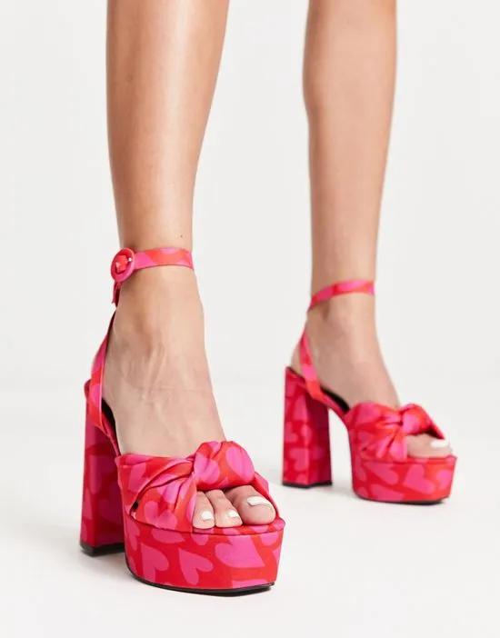 Natia knotted platform heeled sandals in heart print