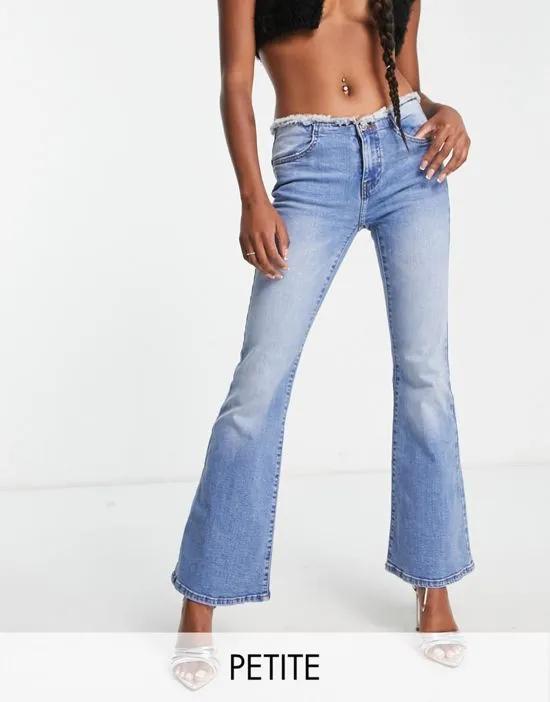 Petite low rise raw waistband flare jean in mid wash blue