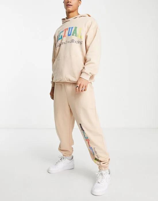 ASOS Actual relaxed sweatpants with multicolor logo print in beige - part of a set