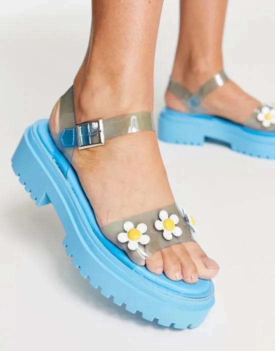 Exclusive flat sandals with daisies in blue vinyl