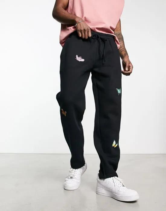 oversized straight leg sweatpants in black with butterfly placement prints and hem split - part of a set