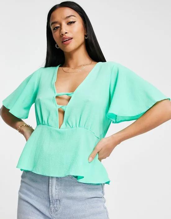 Petite tea blouse with peplum hem and angel sleeves with twist front detail in bright green